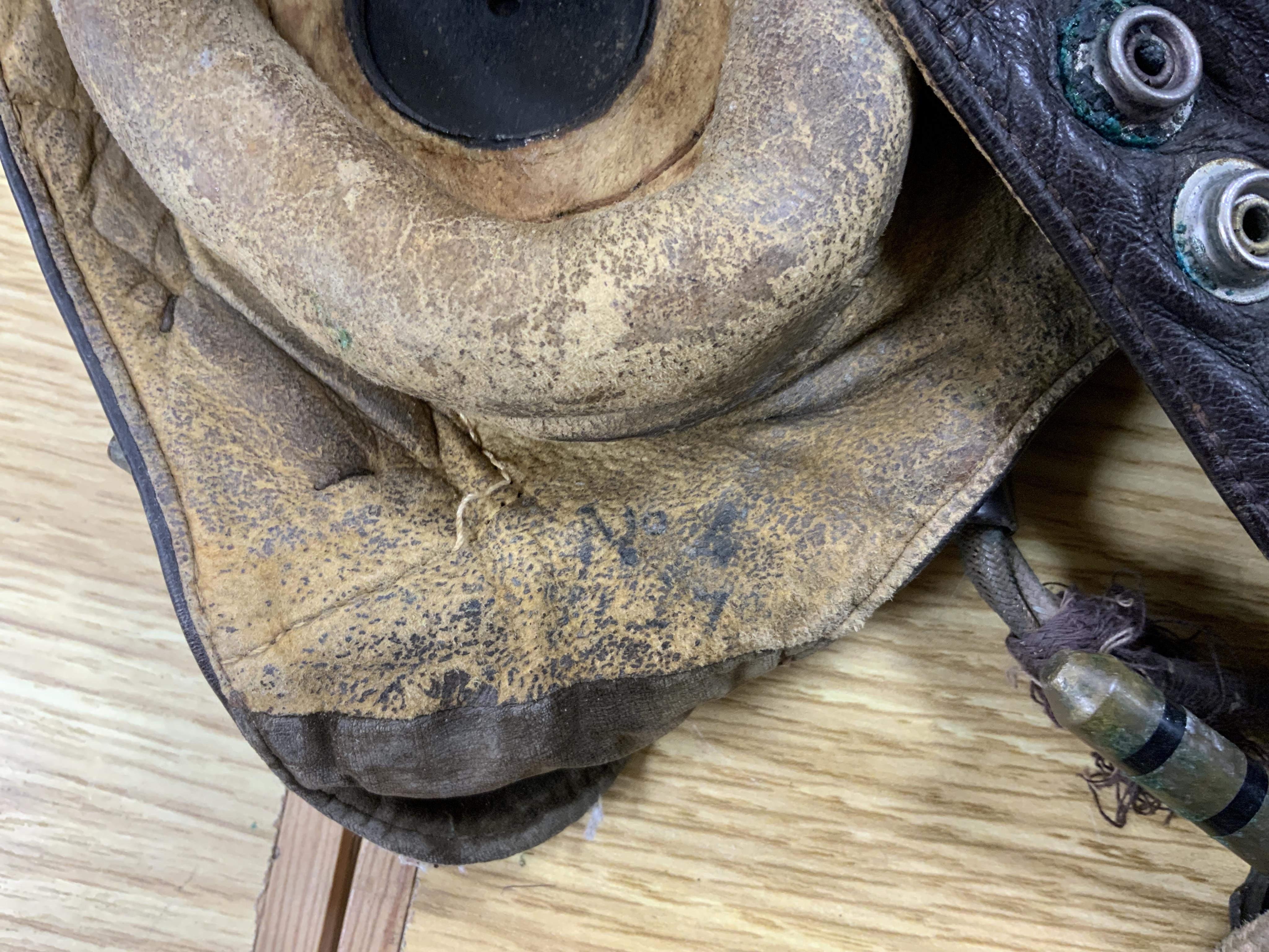A WWII RAF Air Ministry aviator’s leather head-gear, with built-in padded headphones, oxygen mask with microphone and other electrics incorporated into it, marked with a crown and ‘AM 10A/13466’ to one earpiece, together